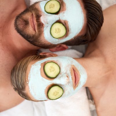 Shot of a young couple wearing cucumbers on their eyes in a spa
